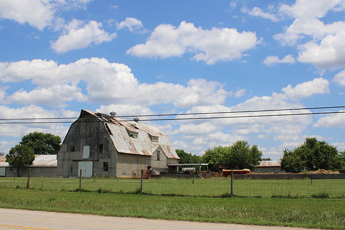 an old decrepit barn sitting in a field under a partly cloudy sky